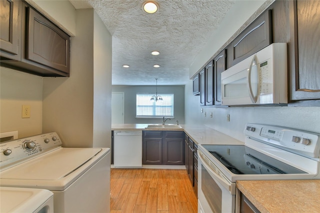 kitchen with white appliances, sink, light hardwood / wood-style flooring, a textured ceiling, and decorative light fixtures