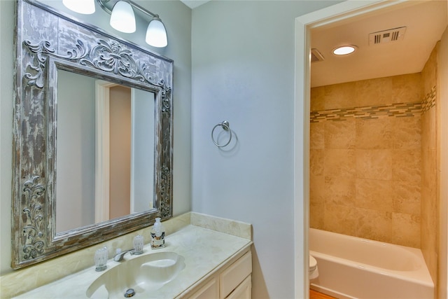 full bathroom with vanity, tiled shower / bath combo, and toilet