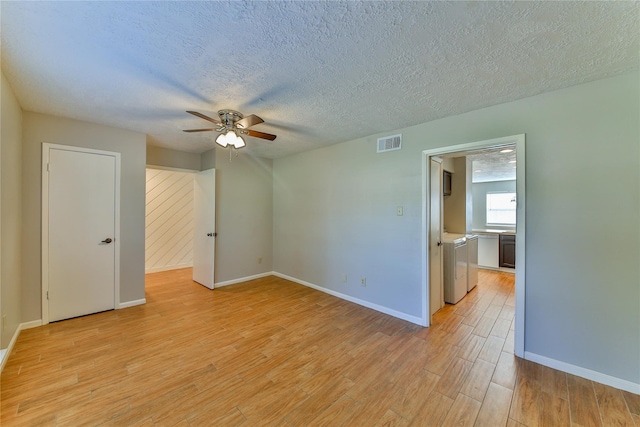 unfurnished room featuring washer and dryer, ceiling fan, light hardwood / wood-style floors, and a textured ceiling