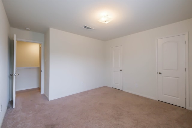 unfurnished bedroom featuring light colored carpet and a closet