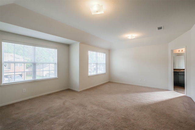 spare room featuring light colored carpet and lofted ceiling