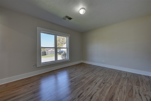 empty room with hardwood / wood-style flooring and a textured ceiling