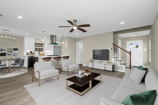 living room with ceiling fan, sink, and light hardwood / wood-style floors