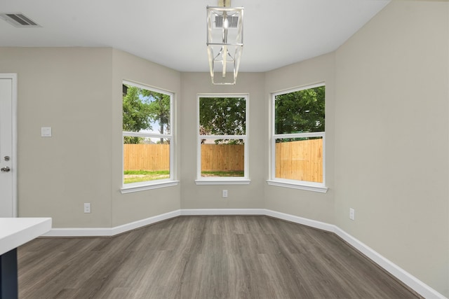 unfurnished dining area with a chandelier, hardwood / wood-style floors, and a wealth of natural light