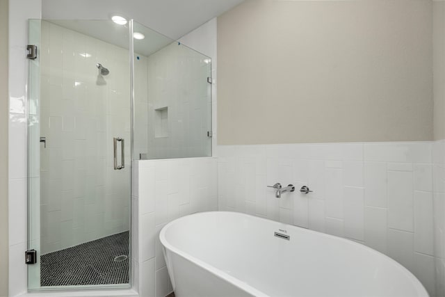 bathroom with shower with separate bathtub and tile walls