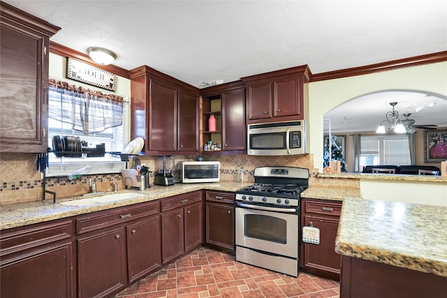 kitchen featuring backsplash, sink, stainless steel appliances, and an inviting chandelier