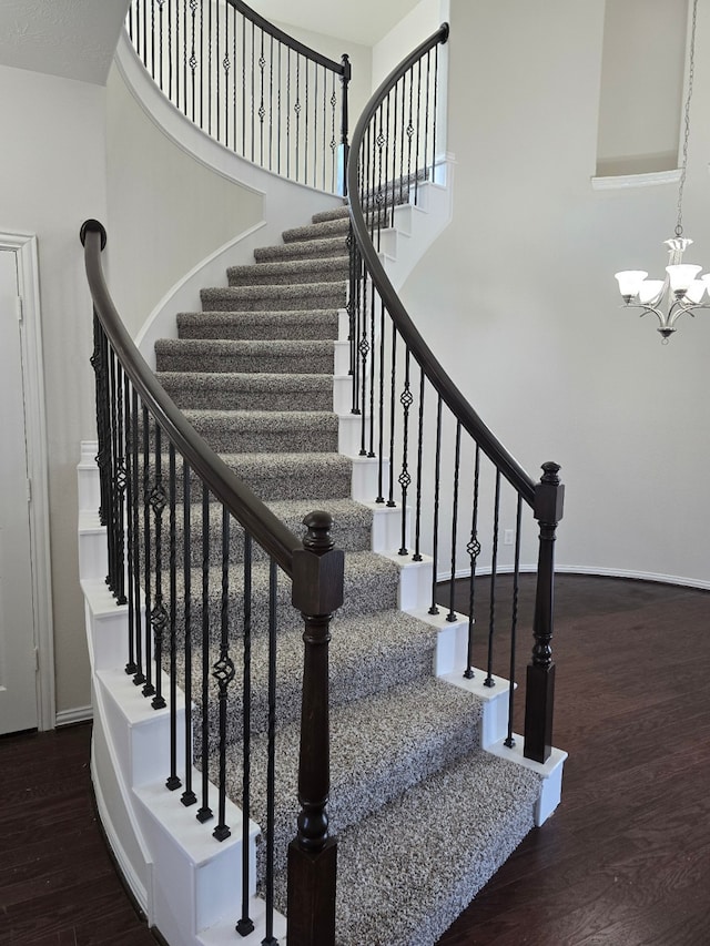 stairway with hardwood / wood-style floors and an inviting chandelier