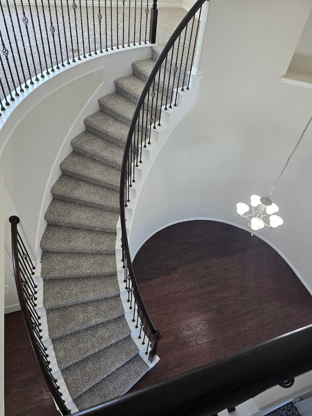 staircase featuring hardwood / wood-style floors and a notable chandelier