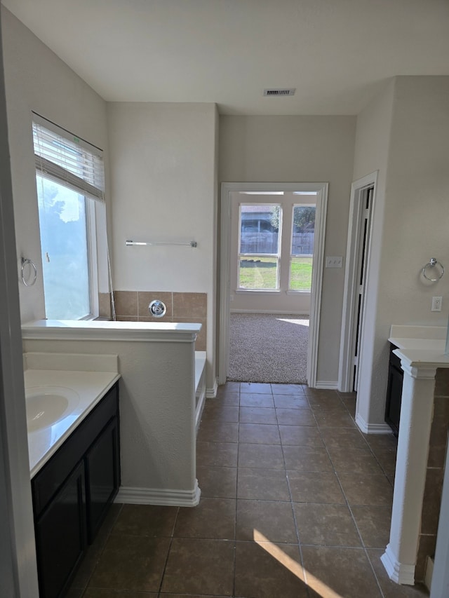 bathroom featuring plenty of natural light, vanity, a bath, and tile patterned flooring