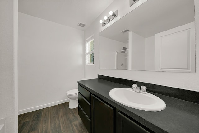 bathroom featuring vanity, hardwood / wood-style flooring, toilet, and walk in shower