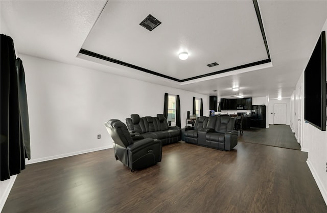 living room with a textured ceiling, a raised ceiling, and dark wood-type flooring