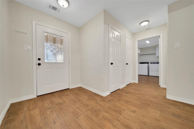 12466 Royal Lake Dr, Conroe, TX 77303 - foyer entrance featuring visible vents, baseboards, light wood-style flooring, and washer and clothes dryer