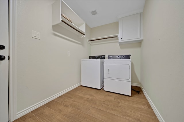 washroom with cabinets, light hardwood / wood-style floors, and washer and clothes dryer