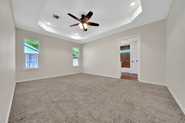 unfurnished room featuring carpet flooring, plenty of natural light, ceiling fan, and a tray ceiling