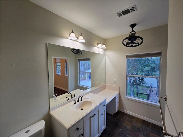 bathroom featuring vanity, a healthy amount of sunlight, and toilet