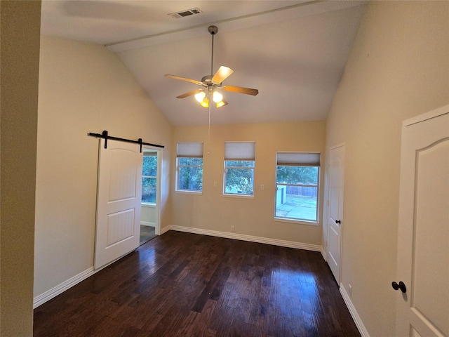 unfurnished room with ceiling fan, a barn door, dark wood-type flooring, and vaulted ceiling