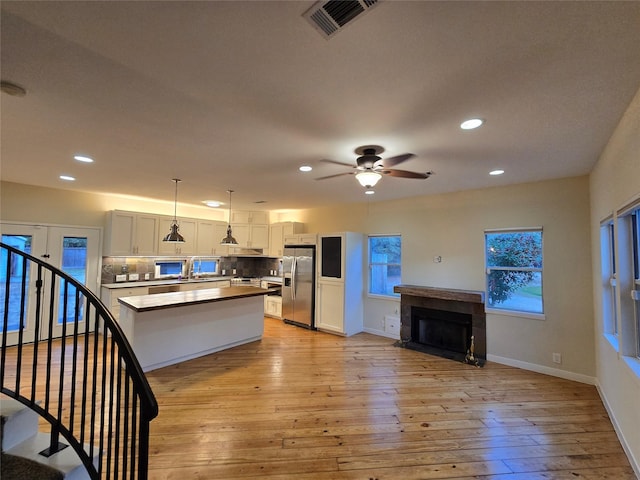 kitchen with white cabinetry, stainless steel fridge with ice dispenser, hanging light fixtures, and light wood-type flooring