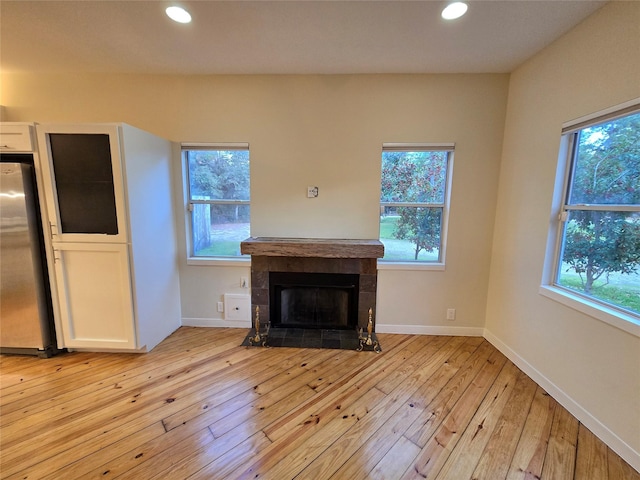 unfurnished living room with a tile fireplace and light hardwood / wood-style flooring