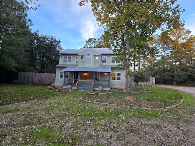 rear view of house featuring covered porch and a lawn