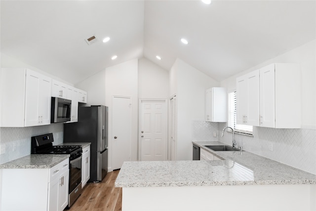 kitchen with white cabinets, sink, stainless steel appliances, and vaulted ceiling