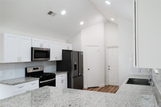 kitchen with sink, light hardwood / wood-style flooring, appliances with stainless steel finishes, tasteful backsplash, and white cabinetry