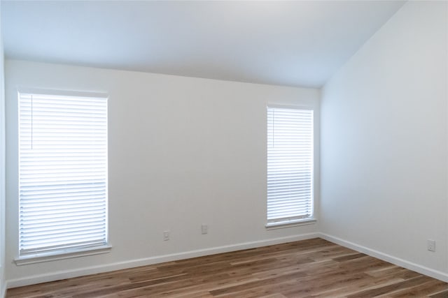 empty room with hardwood / wood-style flooring and lofted ceiling