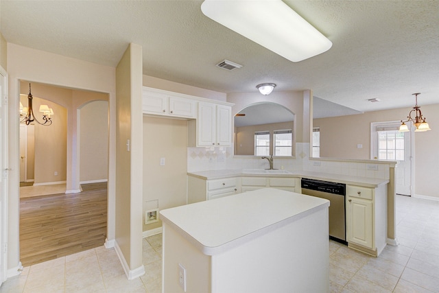 kitchen with dishwasher, a center island, kitchen peninsula, and white cabinetry