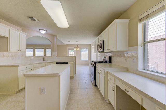 kitchen with decorative backsplash, appliances with stainless steel finishes, pendant lighting, and sink