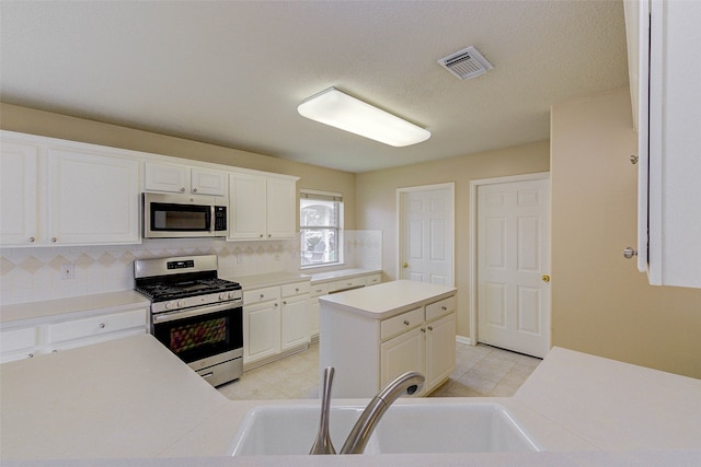 kitchen featuring sink, tasteful backsplash, a kitchen island, white cabinetry, and stainless steel appliances