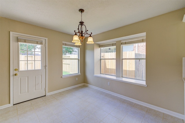 unfurnished dining area featuring light tile patterned floors, a textured ceiling, and an inviting chandelier