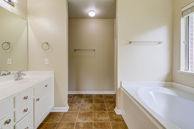 bathroom featuring tile patterned flooring, vanity, a textured ceiling, and a tub