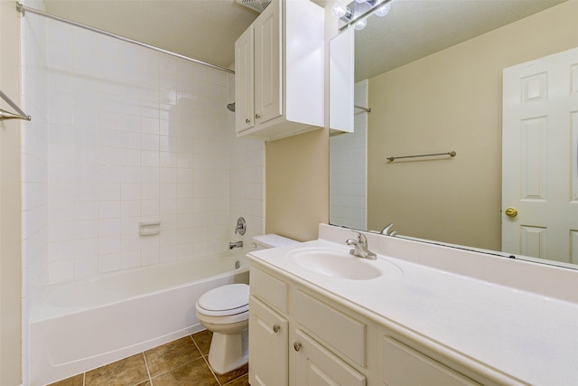 full bathroom featuring vanity, tile patterned floors, tiled shower / bath combo, toilet, and a textured ceiling