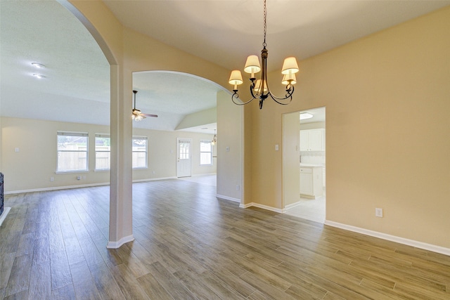 unfurnished room featuring ceiling fan with notable chandelier, lofted ceiling, a textured ceiling, and light hardwood / wood-style flooring