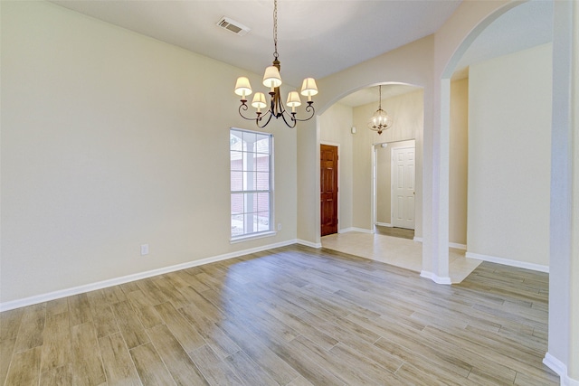 empty room featuring light hardwood / wood-style flooring and a chandelier