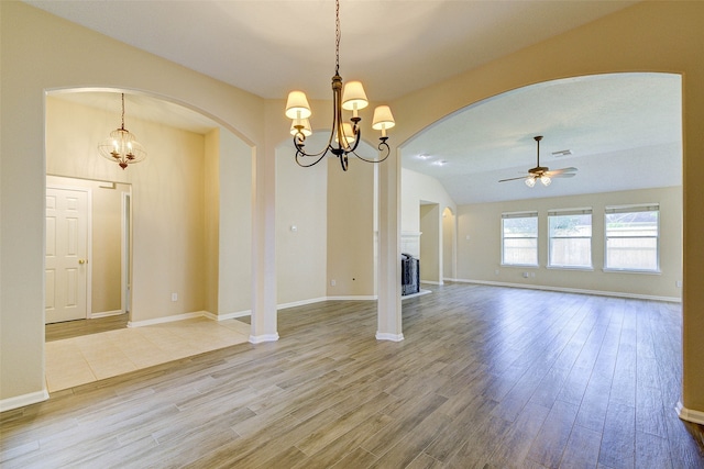 unfurnished living room featuring wood-type flooring, ceiling fan with notable chandelier, and lofted ceiling