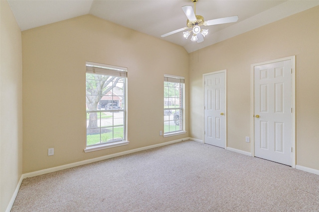 unfurnished bedroom with ceiling fan, two closets, light carpet, and vaulted ceiling