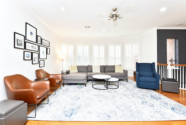 living room featuring hardwood / wood-style floors, ceiling fan, and crown molding