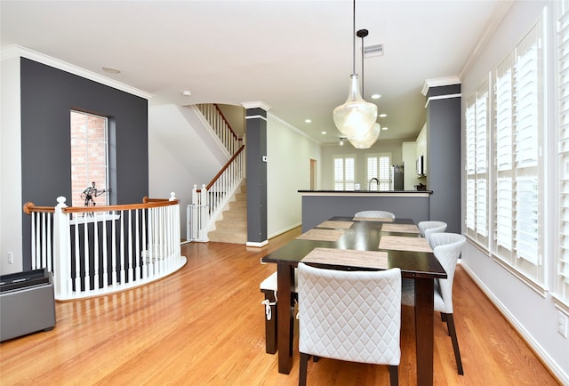 dining area with hardwood / wood-style floors, ornamental molding, and a wealth of natural light