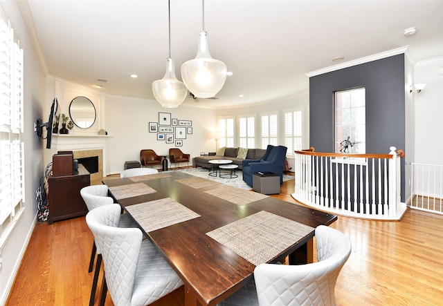 dining room featuring a fireplace, light hardwood / wood-style flooring, and crown molding