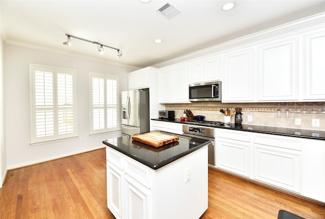 kitchen featuring backsplash, a center island, white cabinets, and stainless steel appliances