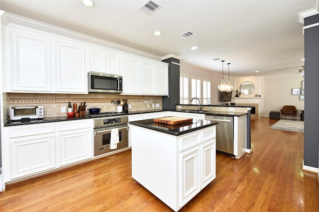 kitchen with white cabinetry, a center island, light hardwood / wood-style floors, pendant lighting, and appliances with stainless steel finishes