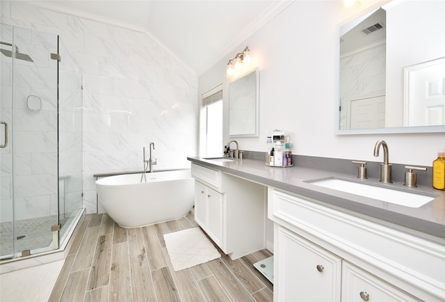 bathroom with separate shower and tub, crown molding, vaulted ceiling, vanity, and tile walls