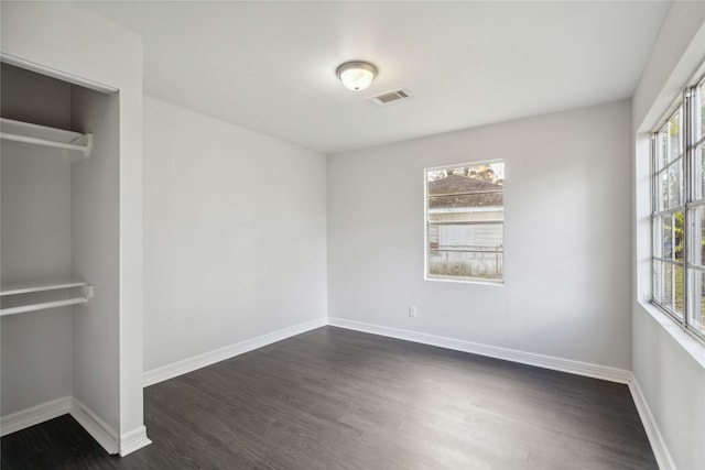 unfurnished bedroom with multiple windows and dark wood-type flooring