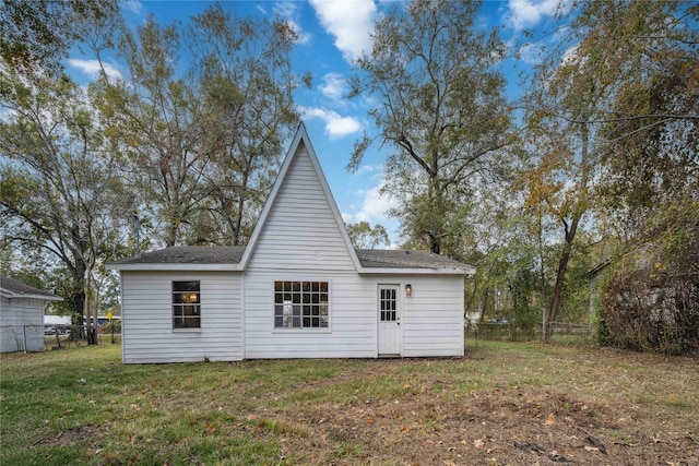 rear view of house featuring a lawn and fence