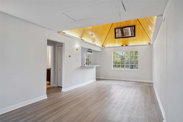 unfurnished living room with lofted ceiling, baseboards, and wood finished floors