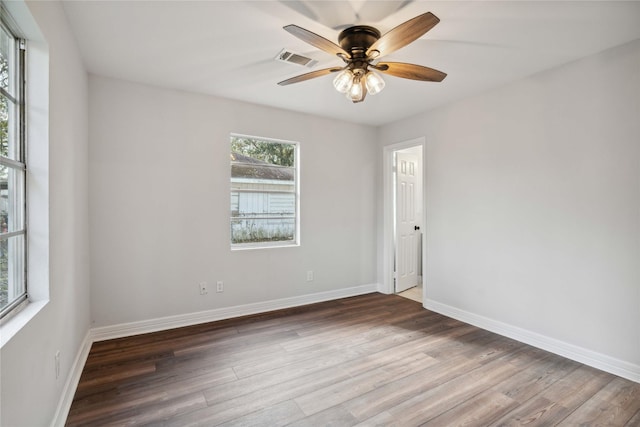 spare room featuring ceiling fan, wood finished floors, visible vents, and baseboards