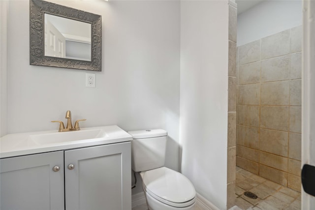 bathroom with toilet, vanity, and tiled shower