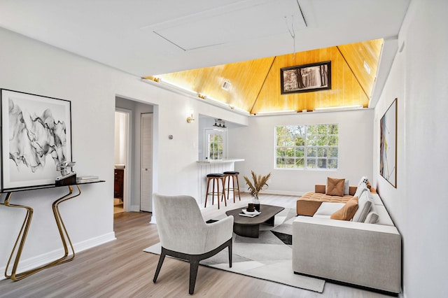 living room with baseboards, wood finished floors, and vaulted ceiling