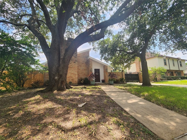 view of front of property featuring brick siding, a front yard, and fence