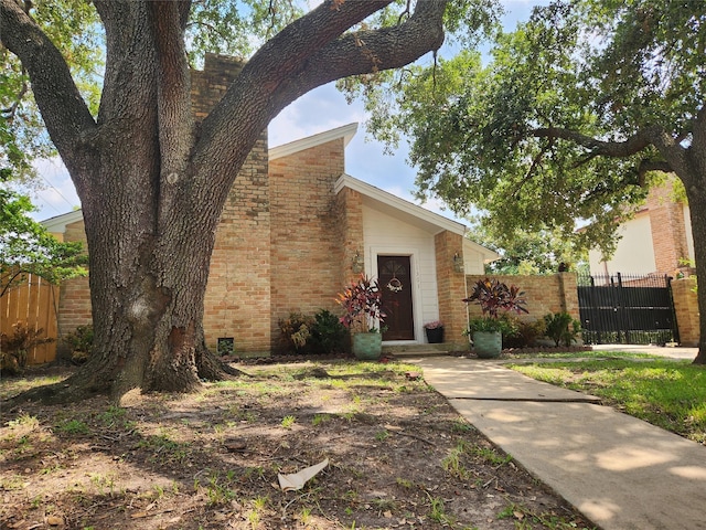 view of front of home featuring brick siding, a gate, and fence